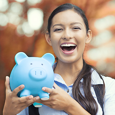 Young woman smiling an holding a blue piggy bank