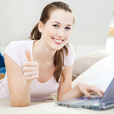 Young woman on laptop giving the camera a thumbs up
