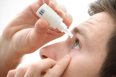 Man putting eye drops in his eyes